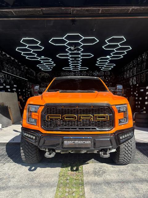 Ford F-150 Raptor laranja na frente da loja